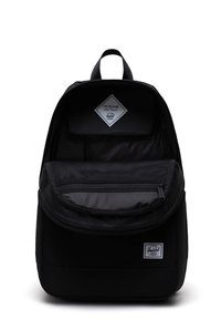 Mochila negra hecha de tela duradera, que cuenta con un compartimento principal con doble cremallera, un bolsillo de malla y una etiqueta con la frase "Póntelo a prueba".