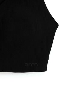 Černý žebrovaný bralet s zakřiveným designem, vybavený jemnou značkovou etiketou. Texturovaná látka poskytuje těsný střih a minimalistický styl.