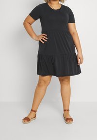 Robe noire à manches courtes avec taille froncée et jupe évasée. Fabriquée dans un matériau doux, elle présente un col rond simple et une longueur au-dessus du genou.