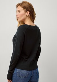 Schwarzer, gestrickter Pullover mit langen Ärmeln, einem gerippten Rundhalsausschnitt und geripptem Saum; glatte Textur, taillierte Passform und schlichtes Design.