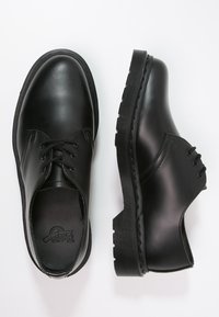 Scarpe in pelle nera con punte rotonde, design con lacci e suole in gomma spesse. Texture liscia, senza motivi o accenti visibili.