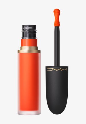 Rouge à lèvres liquide dans un tube transparent rouge-orange avec un bouchon doré. Comprend un applicateur noir avec une pointe texturée orange.