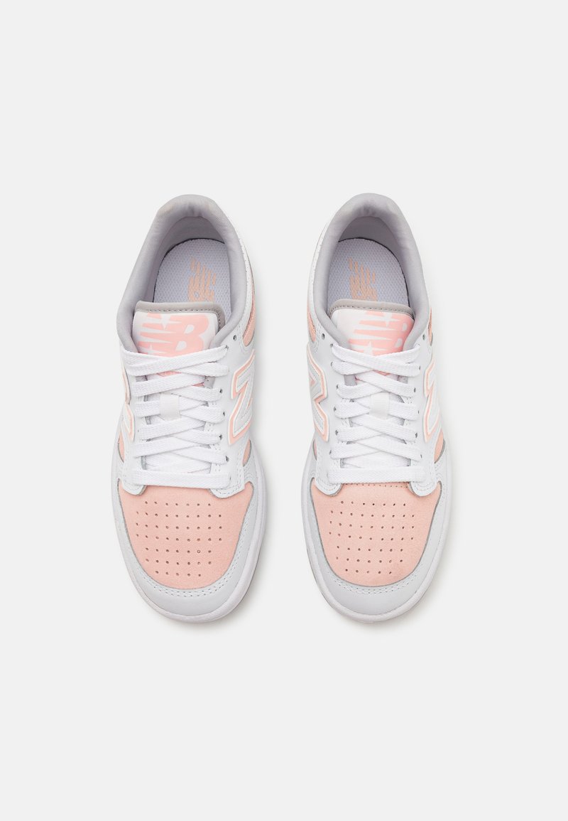 Weiße und hellrosa Sneaker mit einem Obermaterial aus Leder und Mesh, Schnürsenkeldesign, perforierter Zehenbox und prominentem 'N'-Logo an den Seiten.