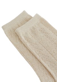 Calcetines de punto en color beige con un patrón texturizado y acentos brillantes. La tela es suave y cuenta con un puño acanalado para un ajuste cómodo.
