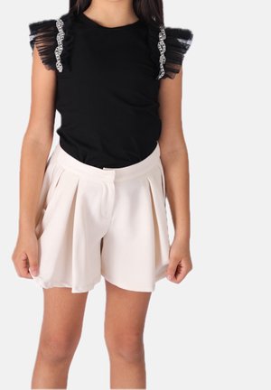 Top negro de manga corta con mangas transparentes con volantes y adornos, combinado con pantalones cortos plisados color beige claro.