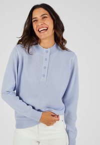 Lichtblauw gebreid trui met een gestructureerde ronde halslijn en knopenlijst met vier knopen. Lange mouwen en ribgebreide zoom.