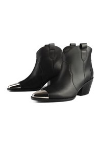 Botines de cuero negro con punta afilada y puntera metálica, que presentan un diseño elegante y un tacón apilado bajo.
