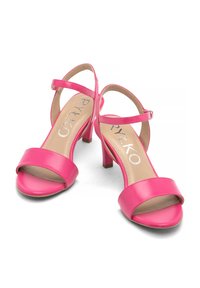 Różowe lakierowane sandały na obcasie z otwartym noskiem i paskiem na kostce. Wyjątkowe cechy to gładka tekstura i średniej wysokości słupkowy obcas.