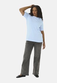 Lichtblauw kortarm shirt met een ontspannen pasvorm, gecombineerd met donkergrijze wijde broek en zwarte platte schoenen. Soepele textuur, casual ontwerp.