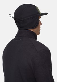 Sort fleeceforlined kasket med et grønt accentpanel, der har en buet skygge og øreflapper, designet til varme og beskyttelse mod koldt vejr.