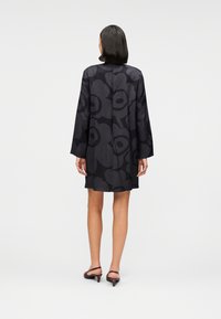 Μαύρο φόρεμα με μακριά μανίκια, διακοσμημένο με λουλουδικό μοτίβο σε διάφορες αποχρώσεις του μαύρου. Κατασκευασμένο από απαλό ύφασμ α, μήκος μέχρι το γόνατο, περιλαμβάνει διακριτικό κλείσιμο στην πλάτη.