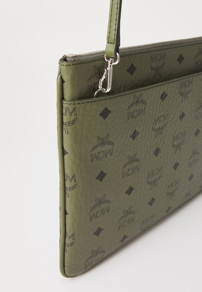 Olívovo zelená textúrovaná kabelka s čiernymi logami MCM a diamantovými vzormi, vybavená strieborným zipsom a odnímateľnou sponou na remeni.