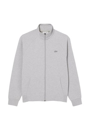 Veste zippée grise en tissu doux, avec des manches raglan, un col haut et deux poches avant. Logo Lacoste sur la poitrine gauche.