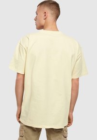 Lys gul bomulds t-shirt med korte ærmer, afslappet pasform og rund halsudskæring. Synlige syninger og glat tekstur.