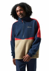 Fleece pullover met een hoge kraag. Beschikt over marineblauwe, rode en beige kleuren in een geometrisch patroon. Textuurstof en ritssluiting.