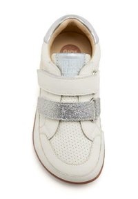 Zapatilla blanca de cuero con textura perforada, acentos plateados en el talón y una tira brillante a lo largo del mediopié. Diseño de puntera redondeada.