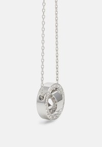 Collana con pendente in argento caratterizzata da un design circolare con un foro centrale, adornato con cristalli trasparenti lungo il bordo, su una catena a maglie.