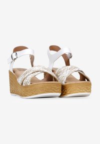 Sandalias wedge blancas con correas trenzadas beige, suela texturizada tipo corcho y tirante ajustable en el tobillo con hebilla de metal.