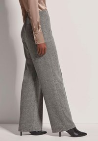 Grijze visgraat wijde broek gemaakt van textuurstof, met een hoge taille en zijzakken, gecombineerd met stijlvolle zwarte hakken.