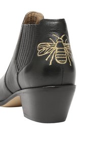 Bottine noire en cuir avec un talon moyen et un motif d'abeille brodé en or sur le talon arrière.