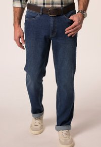 Tmavě modré džíny s rovným střihem, se hnědým páskem a ohrnutými nohavicemi. V kombinaci se svetle barevnými teniskami.