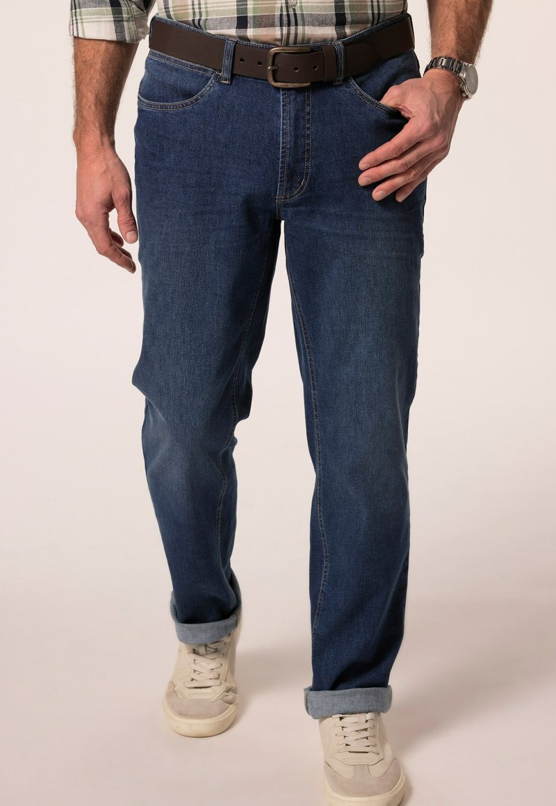 Tmavě modré džíny s rovným střihem, se hnědým páskem a ohrnutými nohavicemi. V kombinaci se svetle barevnými teniskami.