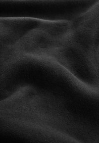 Tessuto nero con una consistenza morbida e liscia, che mostra una drappeggiatura naturale e sottili variazioni di tonalità e dettagli superficiali.