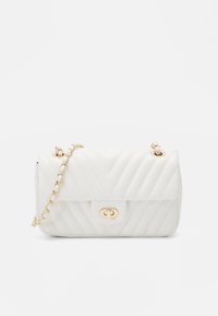 Biała torebka pikowana z złotym łańcuchem na ramię i złotym zapięciem. Powierzchnia ma wzór w zygzaki, co dodaje faktury.