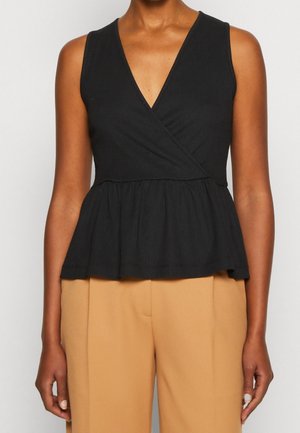 Haut noir sans manches avec un décolleté en V profond et un design portefeuille. Caractérisé par un ourlet à basque et un tissu texturé. Associé à un pantalon beige.