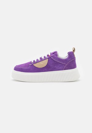 Baskets en daim violet avec une semelle en caoutchouc crème, présentant une accent en daim marron, des lacets blancs et une languette au niveau du talon.
