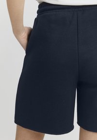 Mørkeblå bomuldsshorts med elastisk talje, der har en blød tekstur og lige snit, der slutter lige over knæene.