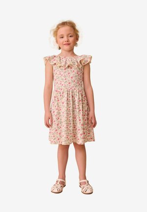 Blumenkleid mit Rüschenausschnitt in Hellrosa, verziert mit kleinen Rosen und grünen Blättern, kombiniert mit beigen Riemchensandalen.