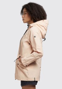 Light pink waterproof jacket with a hood, elastic waist, and pockets. Features black accents and a zipper closure. Made from smooth fabric.