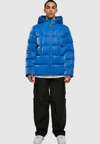Blue puffer jacket with a hood, featuring a quilted design, two zipped front pockets, and a shiny finish. Worn with black cargo pants.
