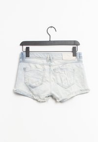 Jeansshorts i ljusblått med fransade kanter, två bakfickor och en tygetikett på midjebandet, hängande på en svart galge.