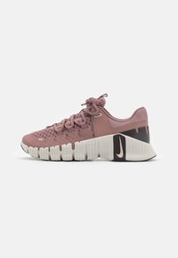 Nike treningssko i myk rosa mesh og gummimaterialer; har avrundet tå, teksturert kropp og flerfarget såle med svarte detaljer.