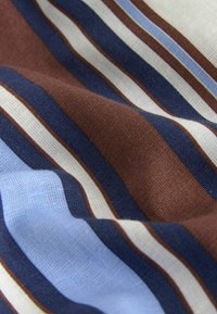 Tissu ondulé avec des larges et fines rayures horizontales en marron, bleu marine, blanc et bleu clair.