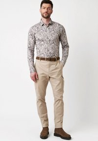Bloemenpatroon overhemden in lichte tinten; gecombineerd met beige cargobroeken en bruine enkellaarzen; heeft een gestructureerde pasvorm en slanke silhouet.