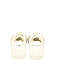 White leather sneakers with textured sides, featuring a smooth finish, rounded toe, and logo detailing on the back.