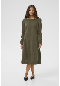 Olivgrön, långärmad klänning med rak silhuett, med en båturringning och rynkade detaljer vid axlarna. Enfärgad tygstruktur.