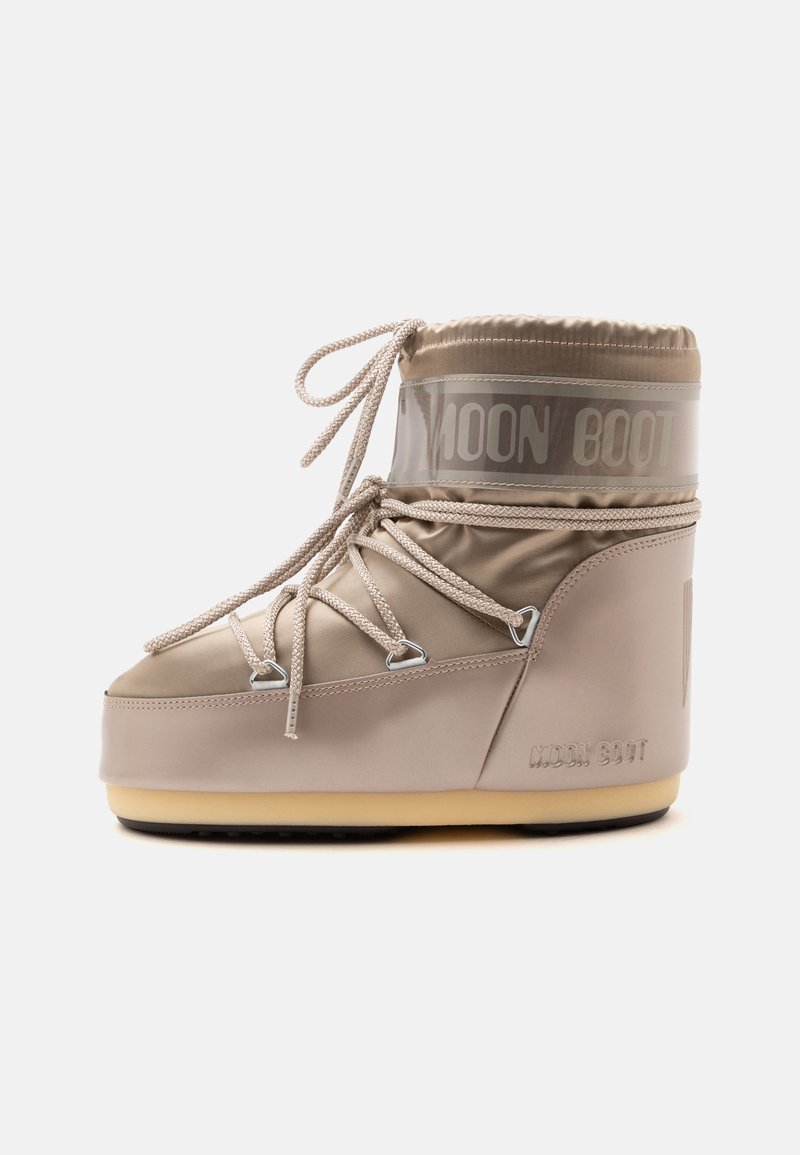 Μπεζ Moon Boot με παχιά σόλα, κορδόνια που σταυρώνονται μπροστά και λογότυπο στην πλευρά και τον αστράγαλο.
