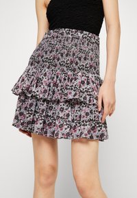 Gonna a fantasia floreale con strati a volant in nero, rosa e bianco. Realizzata in tessuto leggero con una vita arricciata per una vestibilità ottimale.