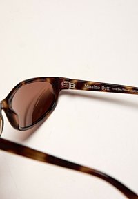 Occhiali da sole tortoise brown con lenti marroni. Presentano una leggera forma a occhio di gatto e hardware metallico sulla stanghetta contrassegnato "Massimo Dutti."