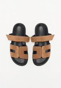 Bruine suède sandalen met twee brede banden, open teenontwerp en zwarte rubberen zolen. Licht gestructureerd oppervlak met uitsnijdingen.