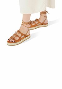Smeđi suede espadrile s vezanjem na gležnjevima, otvorenog dizajna, s platformom od jute i gumene podloge za bolje prianjanje.