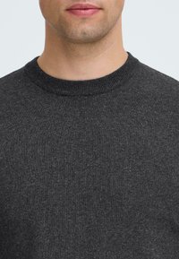 Dunkelgrauer gestrickter Pullover mit rundem Halsausschnitt. Der Stoff ist glatt und leicht strukturiert, mit einer gleichmäßigen Farbe über die gesamte Fläche.