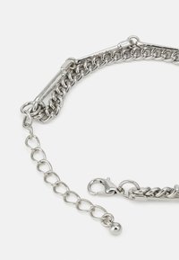 Silver metal chain bracelet featuring interlinked oval and round links, a clasp closure, and an adjustable extension chain with a ball detail.