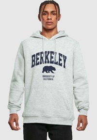 Lys grå hettegenser med "BERKELEY" og logoen til Universitetet i California. Frontlomme med kengurudesign og snøring i hetten. Myk tekstur.