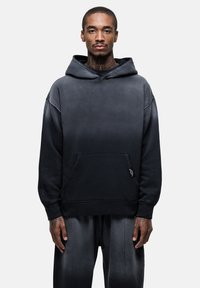 Felpa con cappuccio in una sfumatura di grigio scuro a nero, realizzata in tessuto morbido, con una tasca frontale e una vestibilità comoda con polsini a costine.