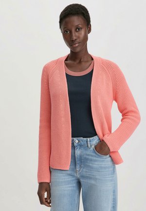 Hellkorallfarbener Strickcardigan mit strukturiertem Muster, offener Front und langen Ärmeln, getragen über einem marineblauen Oberteil und hellblauen Jeans.